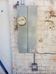 An exterior electrical meter and service panel installed on a brick wall by TJS Electrical Services Inc in Mesa, AZ.