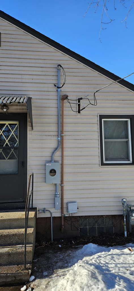 Exterior view of a house showing an electrical meter and service entrance wiring installed by 715 Electric LLC in Eau Claire, WI.