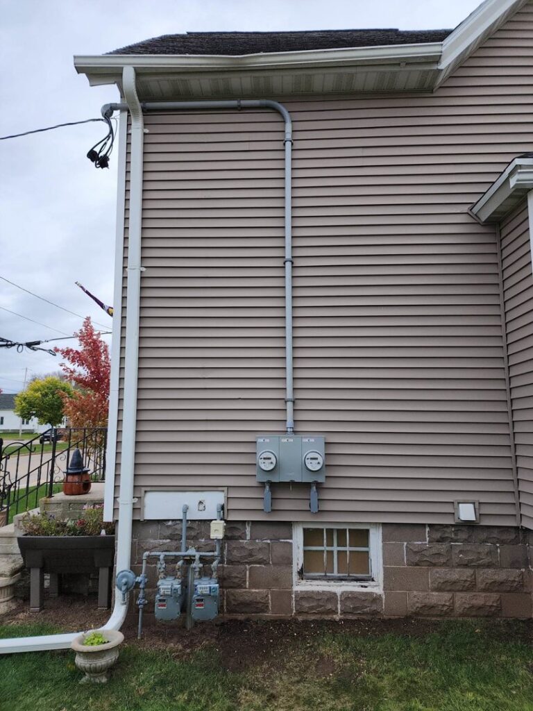 Exterior of a house showing multiple electrical meters and conduit for service upgrades by Apparent Electric LLC in Oshkosh, WI.