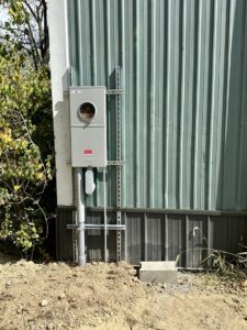 An exterior electrical meter and service entrance conduit installed on the side of a building by Lighten Up Electric, LLC in Cranston, RI.