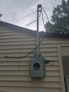 An exterior electrical meter box and conduit on the side of a house, showing service work by J. Bathe Electric in Saint Charles, MO.