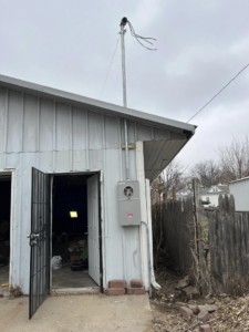 An exterior electrical meter and service mast installation on a building by F&C Electrical Services LLC in Iowa City, IA.