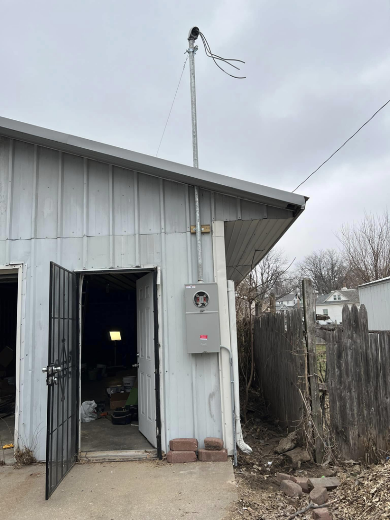 An exterior electrical meter and service mast installation on a building by F&C Electrical Services LLC in Iowa City, IA.