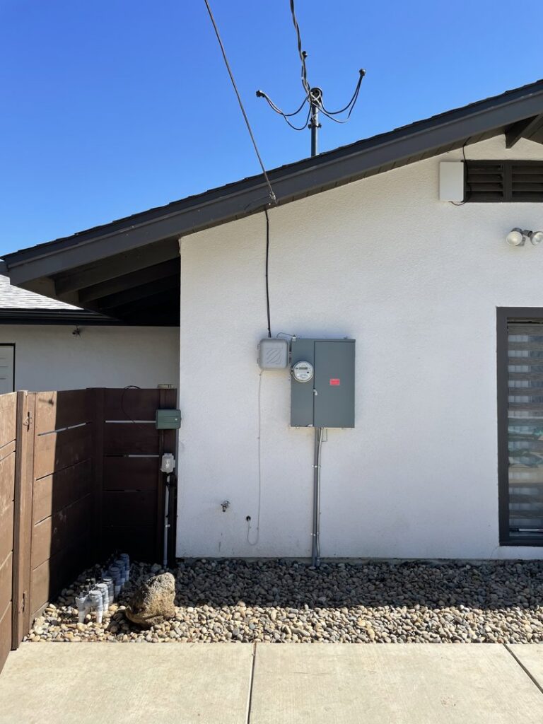 An exterior view of a house showing an electrical meter and service panel installed by Ernco Electric Inc. in Fresno, CA.