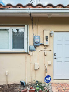 Exterior electrical meter, conduit, and wiring on a building wall, installed by Weglobal Technologies & EEC Electricals in Deerfield Beach, FL