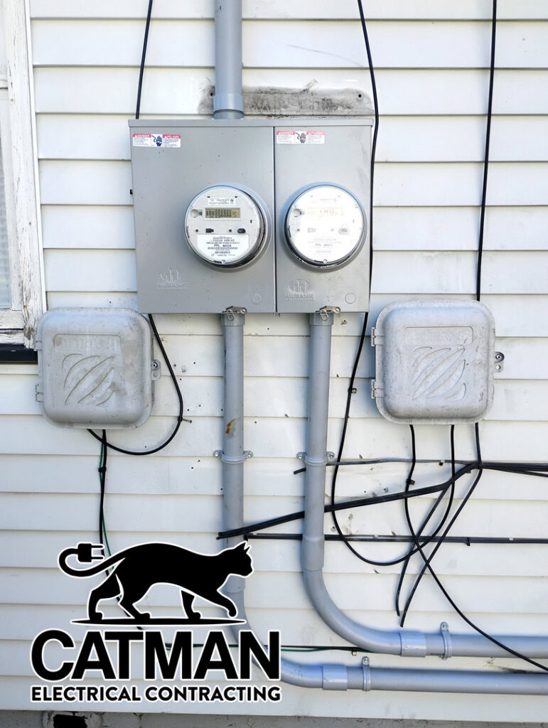 Exterior electrical meters with conduits and junction boxes on a white siding wall, installed by Catman Electrical Contracting in Dallas, PA.