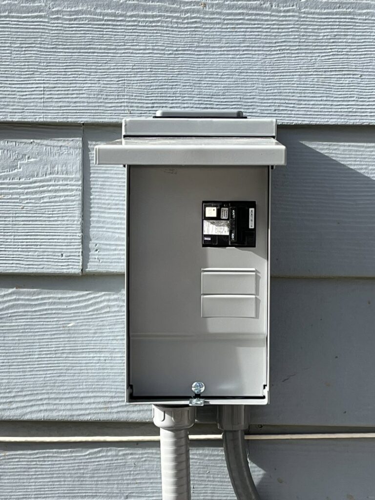 A closed exterior electrical panel with conduit running to it, installed by Mountain Electric in Knoxville, TN.