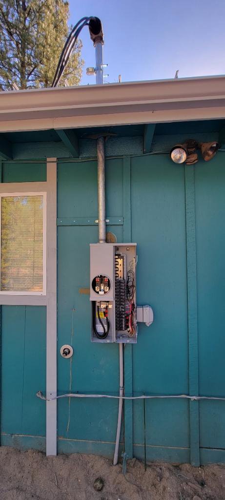 An exterior electrical panel and meter base installed on a blue building by Gold Electric INC in Bend, OR.