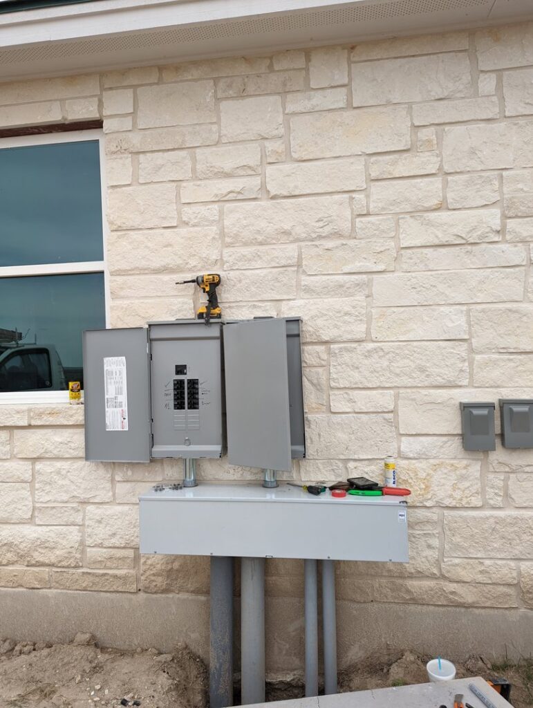 An exterior electrical panel and conduit installation on a stone wall, completed by My A Plus Electric SA in San Antonio, TX