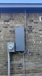 An exterior electrical panel and meter on a brick wall with visible wiring, showing electrical service by Davis Electric in Cleveland, OH.