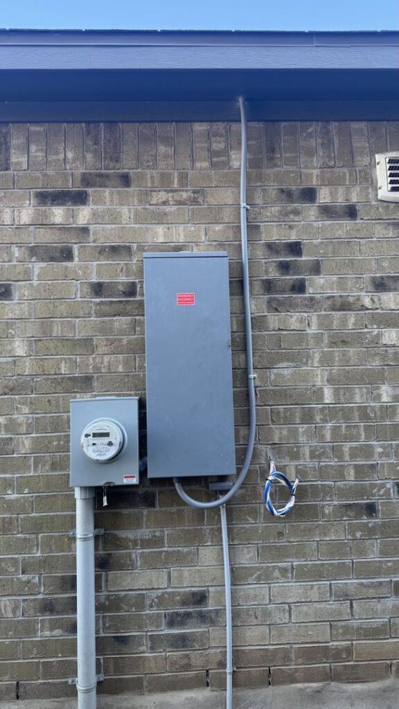 An exterior electrical panel and meter on a brick wall with visible wiring, showing electrical service by Davis Electric in Cleveland, OH.