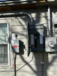 An exterior view of a main electrical panel, meter, and conduit installed on a home by Volt-Pro Electric, LLC in Houston, TX