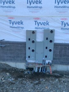 Multiple large electrical panels and meter bases installed on the exterior wall of a building under construction by Interstate Electrical Contractors in Dalton Gardens, ID.