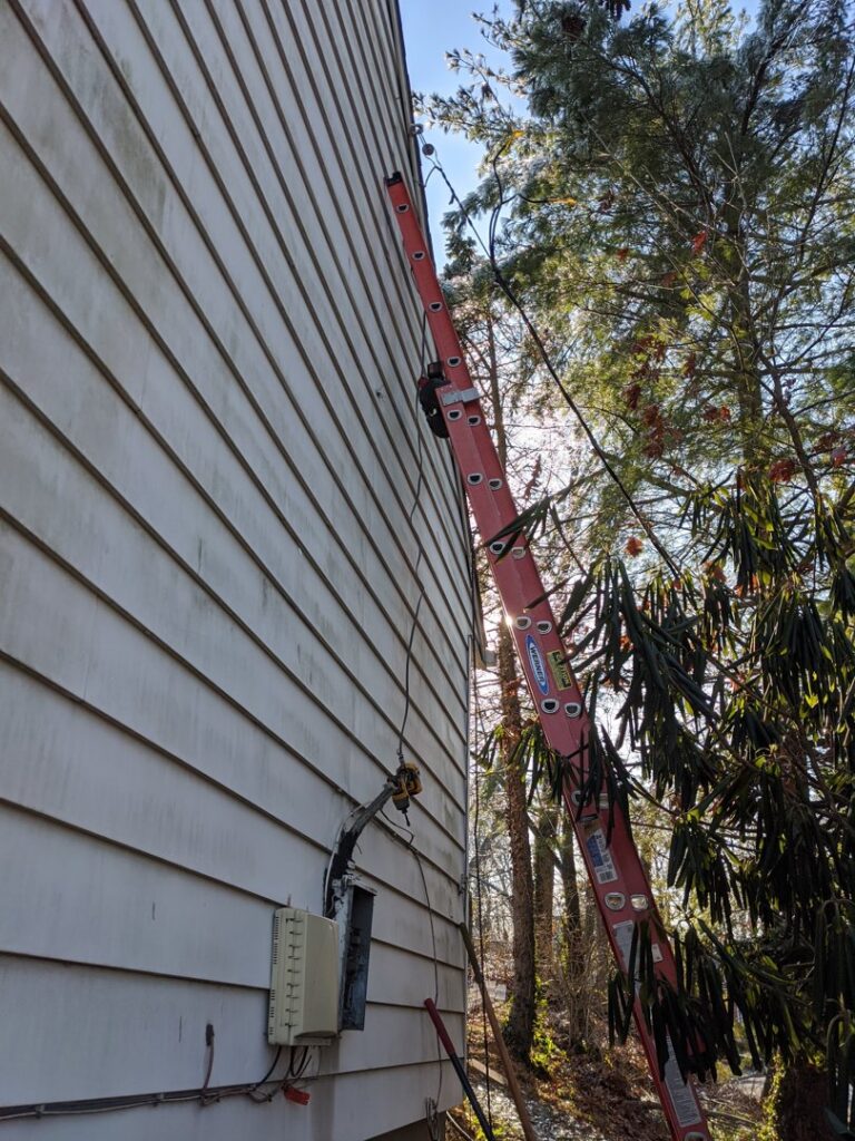 An exterior electrical line repair or installation on a house with a ladder, by York Electric of Westchester in Yonkers, NY.