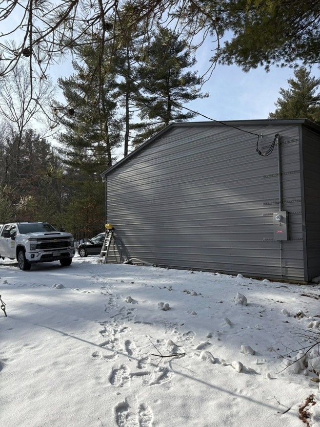 Exterior electrical service installation on a metal building in winter by East West Electric LLC in Chester, NH.