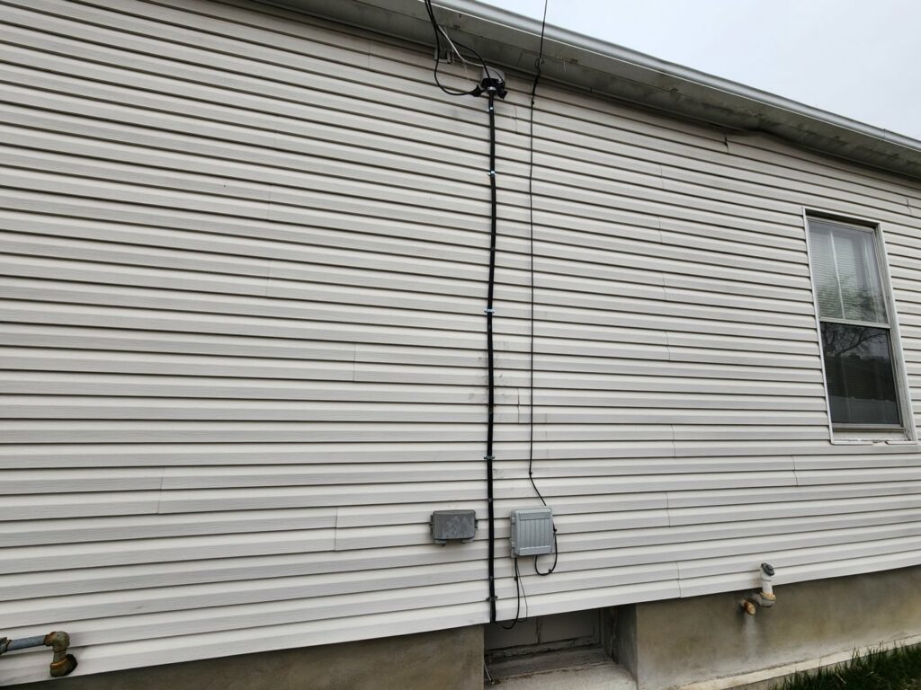 Neatly installed exterior electrical wiring running down the side of a house by Mel Carr Electric in Albany, NY.