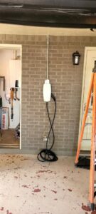An electric vehicle charger professionally installed on an exterior brick wall with conduit by Castle Electrical & Lighting in Scottsdale, AZ.