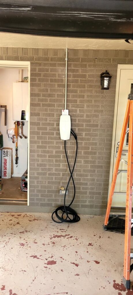 An electric vehicle charger professionally installed on an exterior brick wall with conduit by Castle Electrical & Lighting in Scottsdale, AZ.