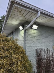 Exterior floodlight installation under the eaves of a building by ABS Electrical Services in Rogers, AR.