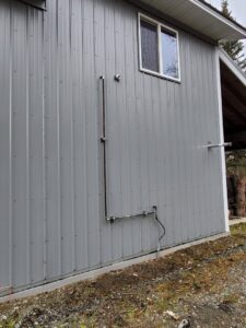 Exterior view of gas line and venting installation on a grey building by HeatSource Mechanical in Wasilla, AK.