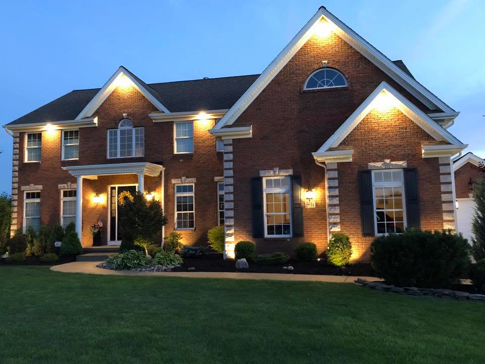 A large brick house showcasing professional exterior lighting installation by Creekside Electric in Clarence Center, NY.