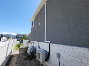 Exterior HVAC piping and conduit installed on a home leading to an outdoor unit by Simple Valley Heating and Cooling in Orem, UT