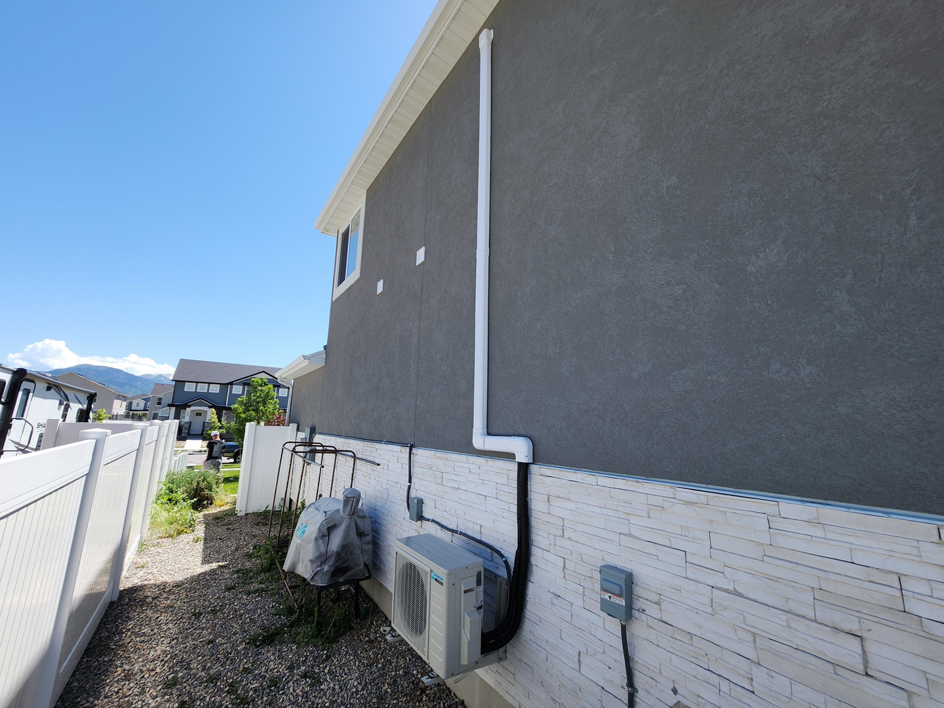 Exterior HVAC piping and conduit installed on a home leading to an outdoor unit by Simple Valley Heating and Cooling in Orem, UT