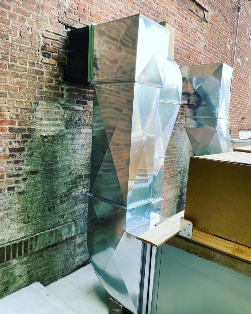 Custom fabricated metal ductwork installed on the exterior brick wall of a building by Deboque Duct Design Corp. in Staten Island, NY