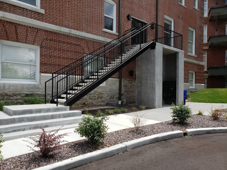 An exterior metal staircase with railings leading to a commercial building, installed by Missouri Ornamental Iron and Fence in St Louis, MO.