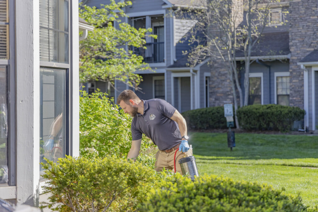 A Berner Pest Solutions technician applying exterior pest treatment around a residential building in Lexington, KY.