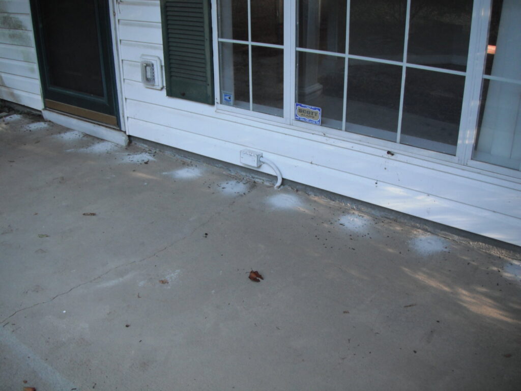 White pesticide dust applied along the exterior foundation of a house for pest treatment by General Pest Solutions in Summerville, SC.