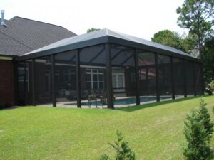 An exterior view of a pool enclosure with a clear glimpse of the swimming pool inside by Backyard Paradise in Mobile, AL.