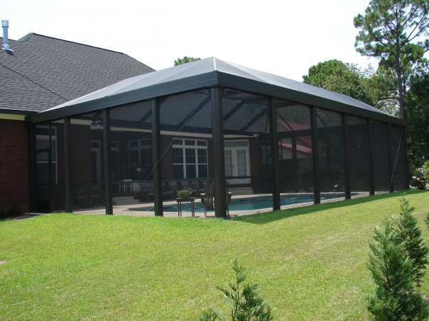 An exterior view of a pool enclosure with a clear glimpse of the swimming pool inside by Backyard Paradise in Mobile, AL.