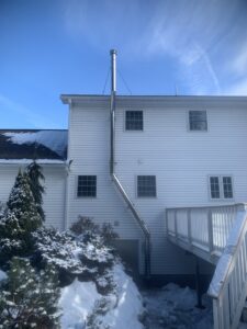An exterior stainless steel chimney pipe installed on the side of a house by Granite State Chimney in Manchester, NH