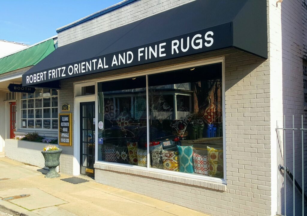 The exterior storefront of Robert Fritz Oriental Rugs, Inc. in Raleigh, NC, featuring a black awning.