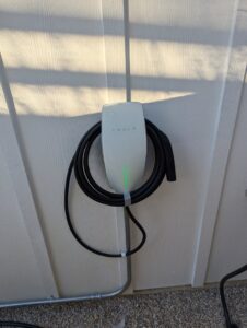 An exterior Tesla EV charger installation on a house wall with conduit, provided by Davis Electric in Cleveland, OH.