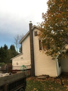 An exterior view of a house showcasing a tall, well-maintained chimney by Cozy Hearth Chimney in South Avington Township, PA.