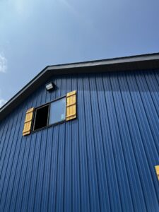 An exterior wall-mounted light fixture visible on a blue metal building, installed by Superior Electrical Solutions llc in Clear Spring, MD.