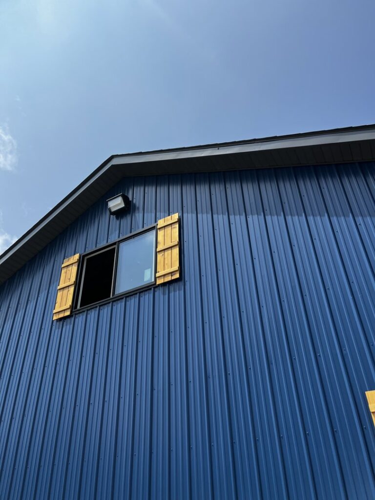 An exterior wall-mounted light fixture visible on a blue metal building, installed by Superior Electrical Solutions llc in Clear Spring, MD.
