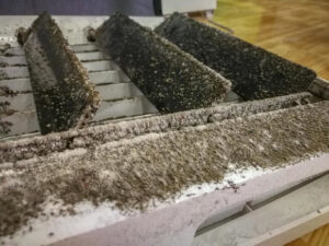 An extremely dirty HVAC air filter or grille, heavily caked with dust and debris, requiring service from Air Doctor Duct Cleaning & Lining in Tulsa, OK.