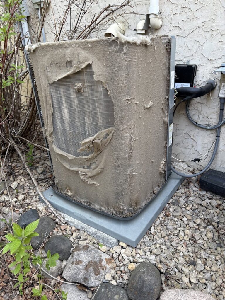 An extremely dirty outdoor air conditioning unit with debris and foliage, indicating a need for cleaning or service by Holzer Heating And Cooling in Savage, MN