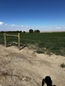 Farm perimeter wire fence with wooden and T-posts by Cowboy State Fencing LLC in Riverton, WY.