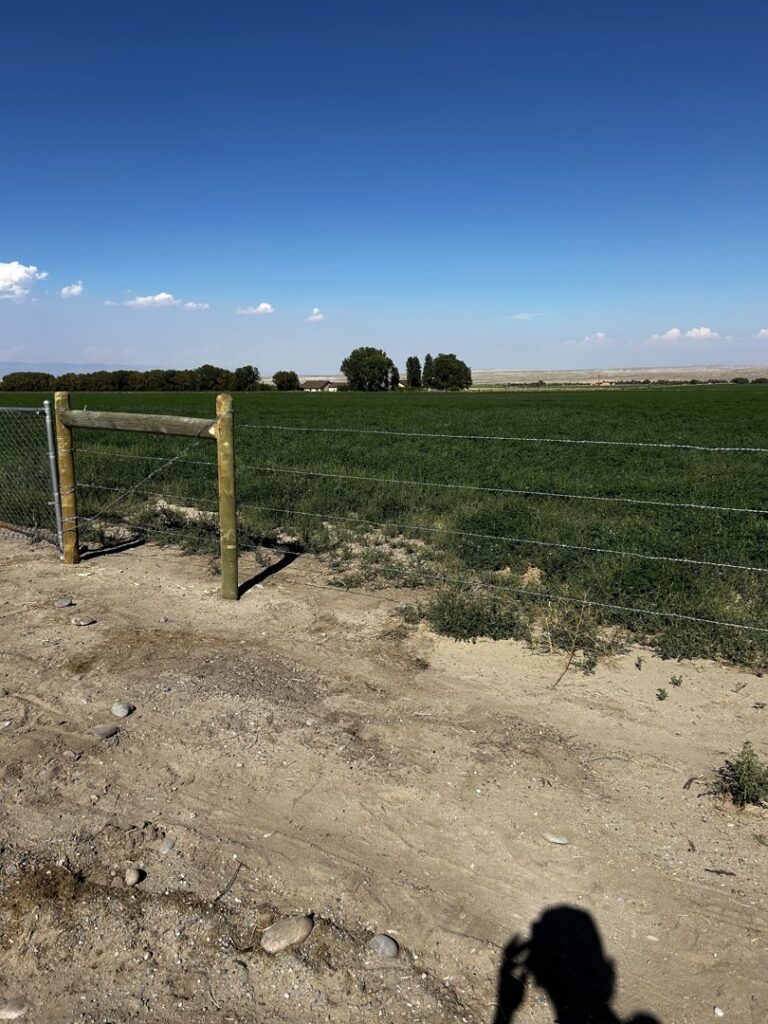 Farm perimeter wire fence with wooden and T-posts by Cowboy State Fencing LLC in Riverton, WY.