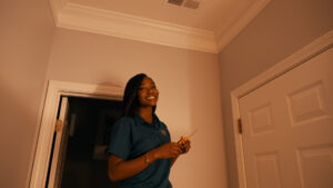 A female HVAC technician smiling while working on a ceiling vent at a client's home for Relief Heating and Cooling, LLC in Greensboro, NC.