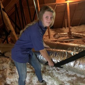 A female HVAC technician working on ductwork in an attic for Ward Mechanical Contractors in Denham Springs, LA.
