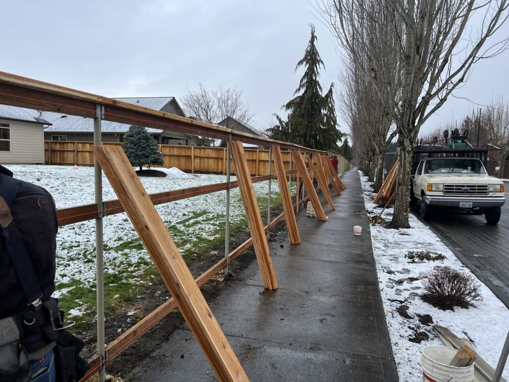 A fence under construction along a sidewalk with snow on the ground, showcasing work by Fence Repair Master in Vancouver, WA.