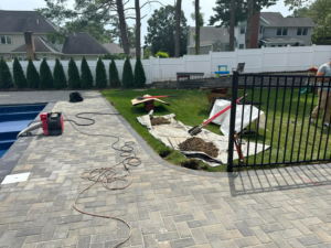 Fencing installation work in progress next to a pool and patio, showing tools and materials by Fenced Up, LLC in Ravena, NY.