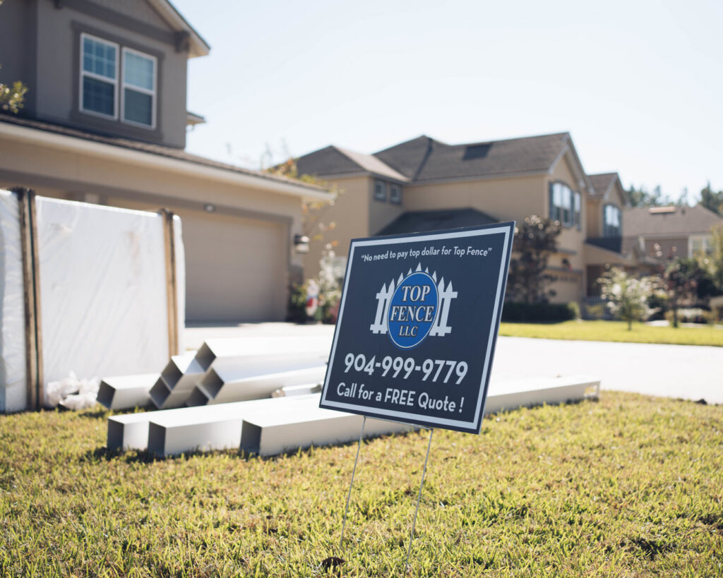 Fence materials and a Top Fence LLC sign on a residential property in Jacksonville, FL, indicating a new fence installation.
