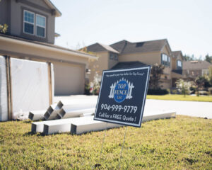 Fence materials and a Top Fence LLC sign on a residential property in Jacksonville, FL, indicating a new fence installation.