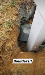 A fence post hole showing a large boulder encountered during installation by Outsiders Fencing in Greensboro, NC.
